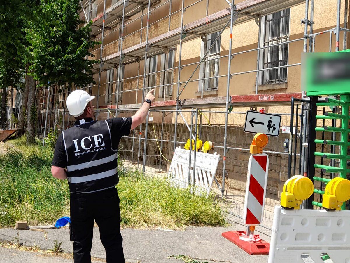 Sicherheitsmitarbeiter von ICE bei der Außenhautkontrolle eines eingerüsteten Gebäudes